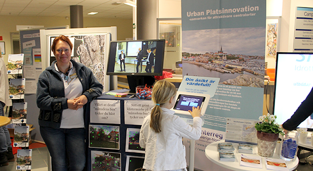 Foto av projektledare Cia Säll och en flicka som använder Touch and Tell-terminalen i Urban Platsinnovations monter på Lysekilsmässan