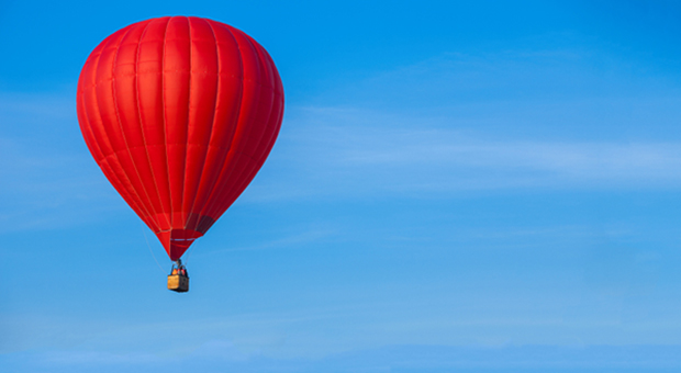 Röd luftballong mot blå himmel.
