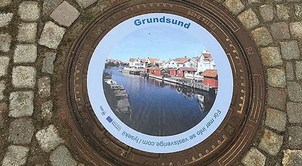 Foto av brunnslock med klistermärke som har ett foto av Grundsund.